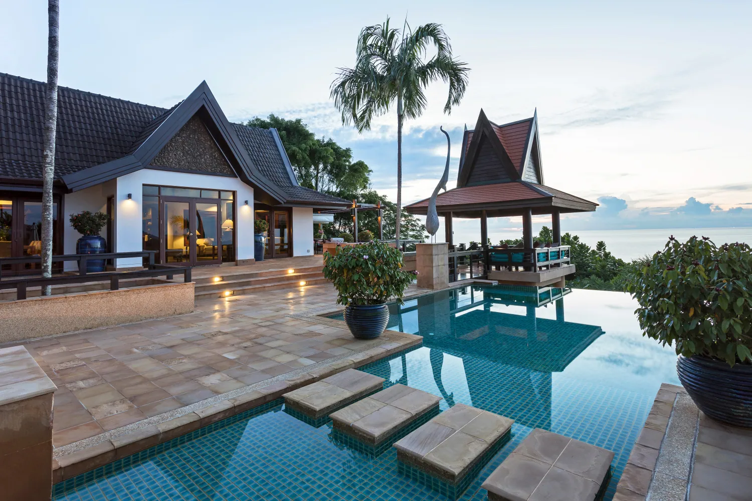 The main pavilion and the sala lit at dusk above the infinity pool